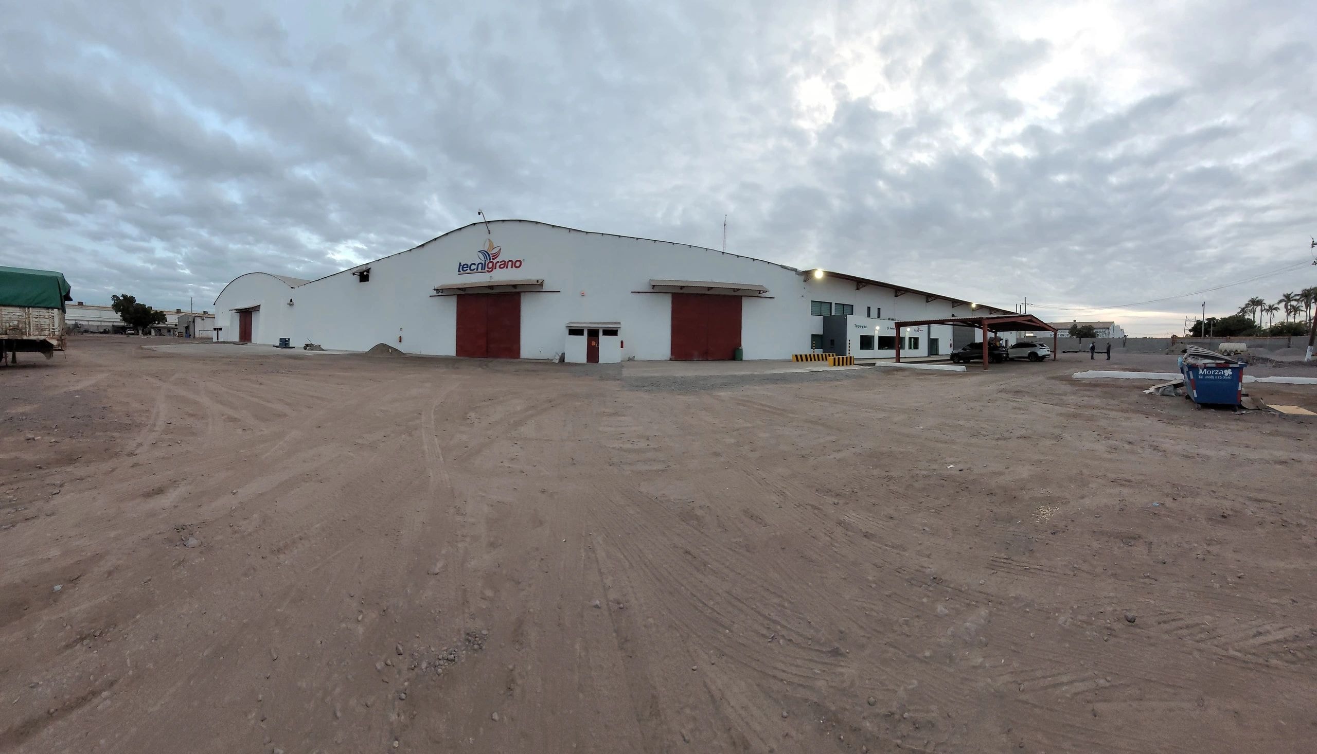 Bodega industrial de Tecnigrano con techo blanco y puertas rojas